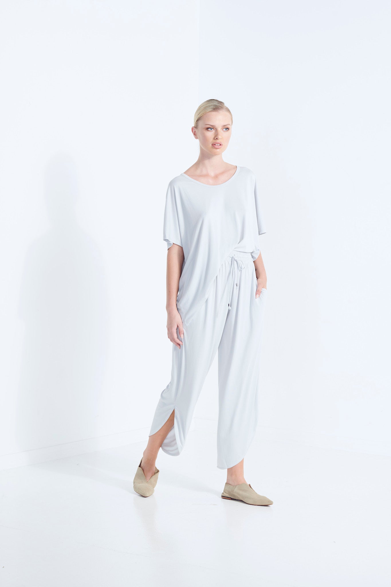 BELU PANT WISP PALE WASHED GREY LUXURY LOUNGEWEAR RELAXED KNIT PANTS WITH ELASTIC WAIST AND PETAL HEM WALKING  SIDE VIEW