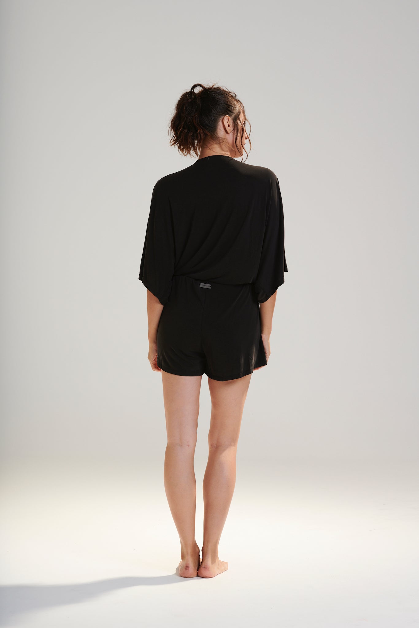 CARRIE PLAYSUIT BEECHWOOD MODAL STRETCH ROMPER  WITH WRAP FRONT TIE WAIST AND POCKETS IN DARK WASHED BLACK BACK MOVEMENT VIEW